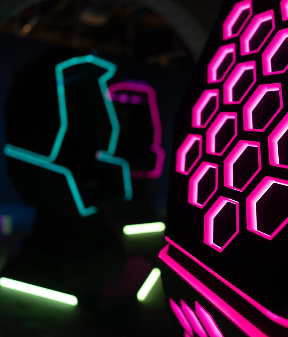 Butacas con movimiento perfiladas con luz de neón junto a un panel hexagonal luminoso